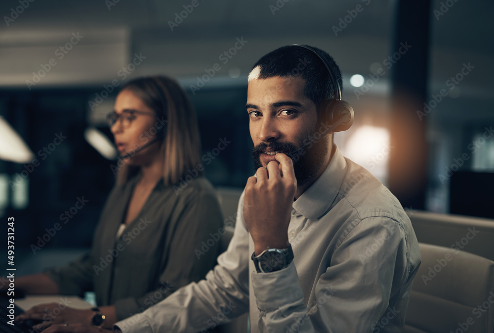 Poster We know how to build good relationships with our customers. Portrait of a call centre agent working in an office alongside a colleague at night.