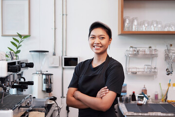 Asian Young barista woman is wearing apron standing and Smiling for happy at counter bar in cafe. Start up for Coffee shop and cafe business owner concept.