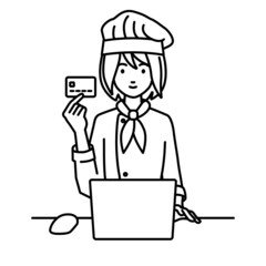 デスクで座ってPCを使いながらクレジットカードを手に持っている調理師の女性