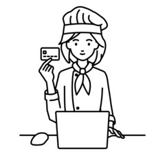 デスクで座ってPCを使いながらクレジットカードを手に持っている調理師の女性