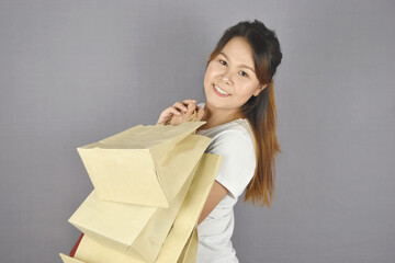 Portrait of happy smiling woman holding shopping bag on grey background.