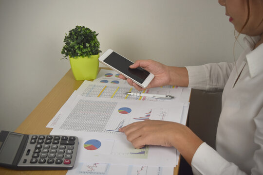 businesswoman working analyzing financial graphs and charts report on desk in office.