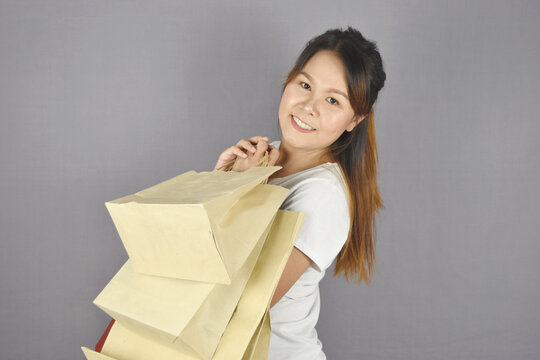 Portrait of happy smiling woman holding shopping bag on grey background.