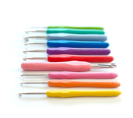 Colorful crochet hooks in different sizes for knitting isolated on white background in soft focus