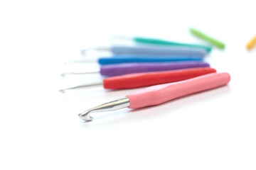 Colorful crochet hooks in different sizes for knitting isolated on white background in soft focus