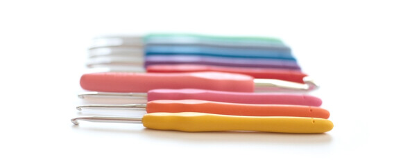 Blurred colorful crochet hooks in different sizes for knitting isolated on white background
