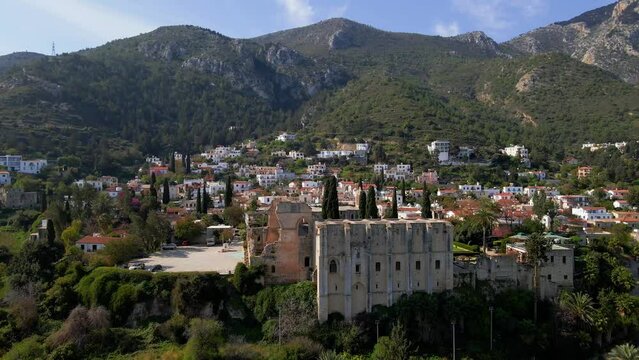 Aerial 4K view of beautiful Bellapais Village with Bellapais Monastery in Kyrenia, North Cyprus surrounded with an amazing green Mediterranean nature and picturesque landscapes in Cyprus.