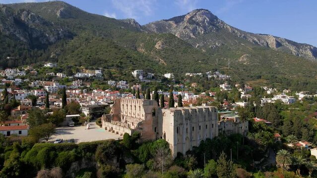 Aerial 4K view of beautiful Bellapais Village with Bellapais Monastery in Kyrenia, North Cyprus surrounded with an amazing green Mediterranean nature and picturesque landscapes in Cyprus.