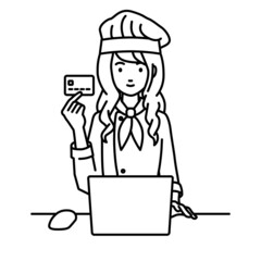 デスクで座ってPCを使いながらクレジットカードを手に持っている調理師の女性