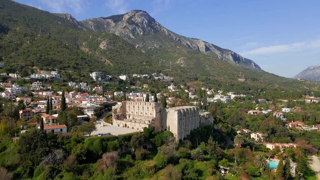 Aerial 4K view of beautiful Bellapais Village with Bellapais Monastery in Kyrenia, North Cyprus surrounded with an amazing green Mediterranean nature and picturesque landscapes in Cyprus.