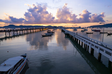 Fototapeta premium Aerial View Top down Drone shot of Yacht and sailboat parking in marina at Chalong bay Transportation and travel background concept.Beautiful sea with mountain sunrise sky clouds sunset background