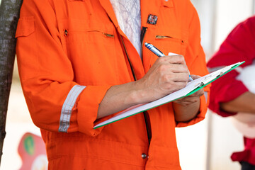 Safety officer or Supervisor is writing note on the checklist paper during perform audit and...