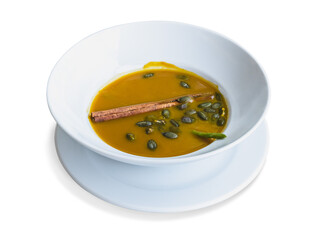 Pumpkin soup with pumpkin seeds and cinnamon served in white bowl