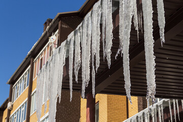 thaw, long icicles hang from the roofs of houses, spring icicles, spring, ice melts from the roofs, warm spring