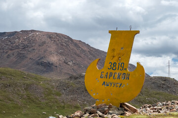 Stella on the road to Kumtor gold mine with inscription in Kyrgyz language -  " 3919m Barskoon mountain pass".