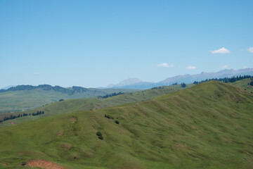 Beautiful green mountains with blue sky background. Santash mountain pass in Kyrgyzstan.