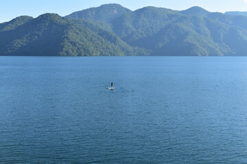 Obraz premium 山と湖に浮かぶスタンアップパドルボート