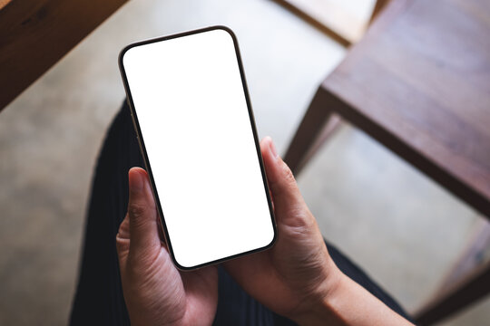 Top view mockup image of a woman holding mobile phone with blank desktop screen