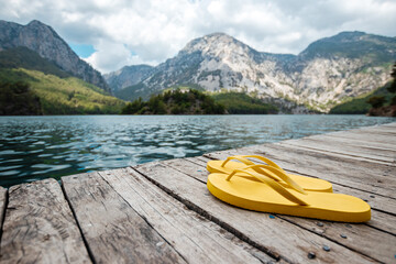 Slippers on the beach, on the pier. Beautiful landscape, mountains and lake. summer holidays,...