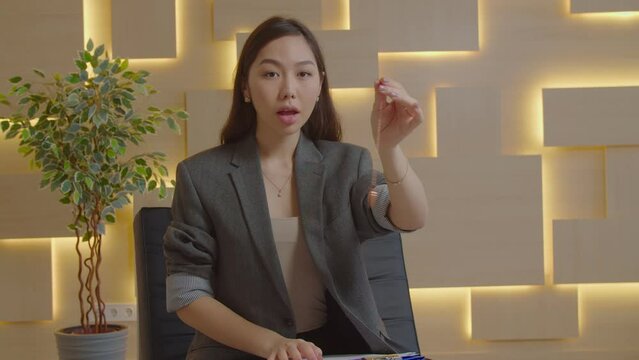 Serene pretty Asian woman mental health professional holding pendulum, hypnotizing patient, to create state of focused attention and increased suggestibility in treatment of psychological disorder.