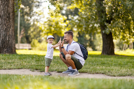 A father and son playing a hand clap game in nature.
