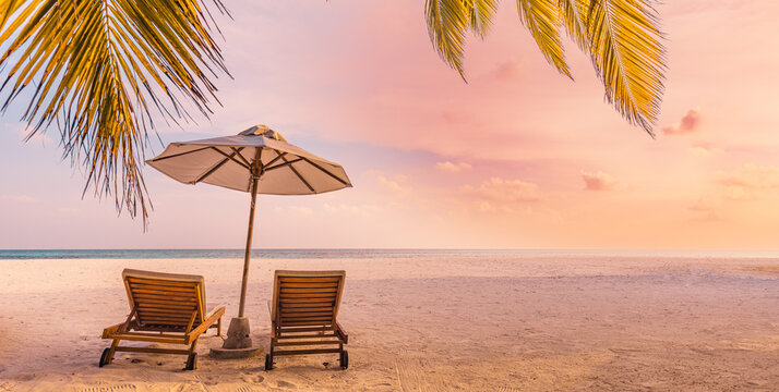 Beautiful panoramic nature. Tropical beach sunset as summer island landscape with chairs umbrella palm leaves calm sea shore, coast. Luxury travel panoramic destination banner for vacation or holiday © icemanphotos