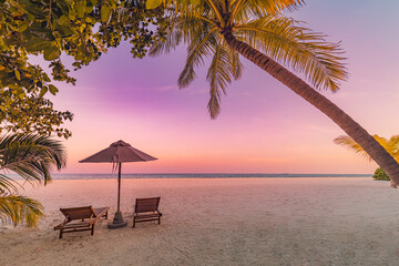 Fototapeta na wymiar Perfect tropical sunset scenery, two sun beds, loungers, umbrella under palm tree. White sand, sea view with horizon, colorful twilight sky, calmness and relaxation. Inspirational beach resort hotel