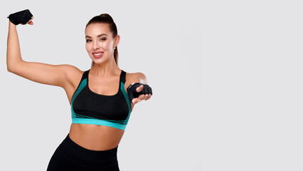 Fototapeta premium Attractive caucasian strong fitness woman shows strong hands, sporty female with perfect body. Healthy lifestyle and beauty concept