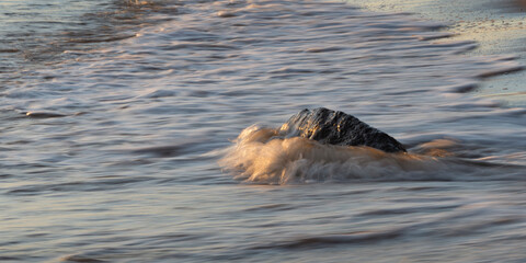 Obraz premium Ocean waves crashing on the rocks at beach at sunrise