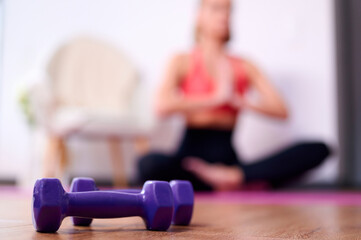 Fototapeta na wymiar Selective focus woman doing physical exercises doing yoga at home sit on mat with dumbbell ami