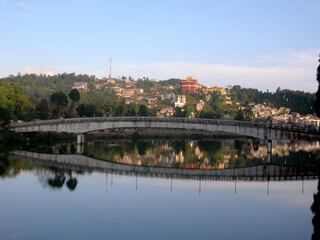 Fototapeta na wymiar The small hill town mirrored at Sumendu Lake look mesmserizing at Mirik in Darjeeling. This is an old artificial lake measuring around 1.25 km long and main attraction of the place.