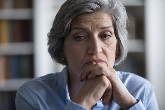 Close up worried middle-aged woman deep in sad thoughts, troubled with business or personal life concerns. Frustrated businesswoman thinks seated at workplace, feel distressed looks helpless concept