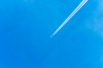 An air plane fly over the clear blue sky with contrail behind.