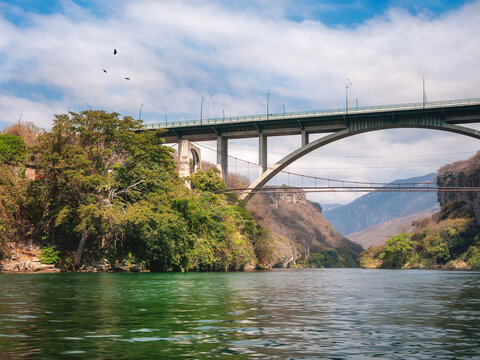 A high bridge connecting the two banks of Grijalva river in the colonial town of Chiapa de Corzo. View from the water on a boat tour of the Sumidero Canyon in Chiapas, Mexico.