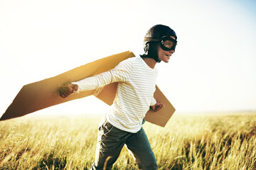 Ready for lift off. Shot of a young boy pretending to fly with a pair of cardboard wings in an open...