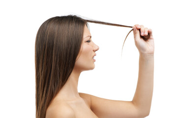 Struggling with split ends. A beautiful young woman frustrated by her split ends while isolated on a white background.