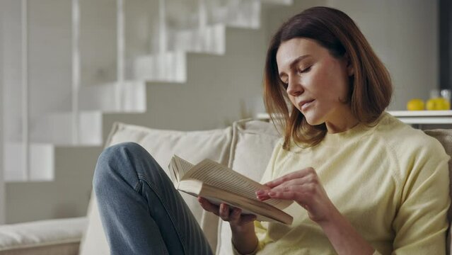 Beautiful woman sitting on sofa and reading book