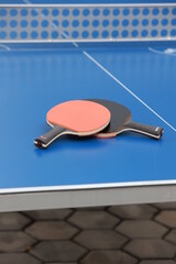 Raquettes de tennis de table posées sur une table bleue en extérieur