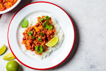 Chili con carne - minced meat with vegetables and beans in tomato sauce with rice in bowl. Mexican food concept.