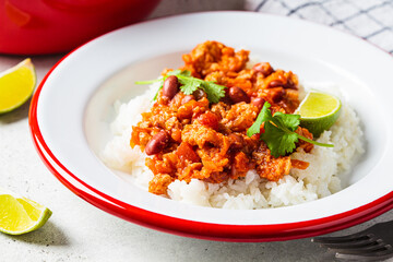 Chili con carne - minced meat with vegetables and beans in tomato sauce with rice in bowl. Mexican food concept.