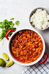 Vegan chili con carne with vegetables and beans in tomato sauce in a red saucepan. Mexican food concept.