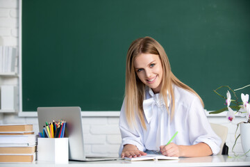 Female student writing on notebook on lesson lecture in classroom at high school or college.