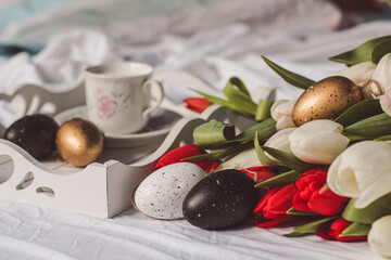 Sill life spring white and red tulips with golden and white easter eggs