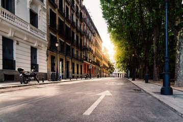 Street in central Madrid at early morning with sunflare on background. Calle San Quintin