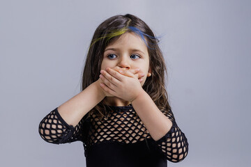 the child covers his face with his hands with the symbols of the blue-yellow flag of Ukraine....