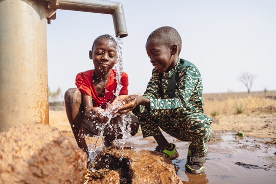 African young children drinking fresh clean water from a tap.
