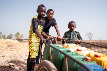 African young boys transporting water on a pushcart for the needs of their community,water scarcity...