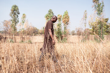 Despaired farmer walking in a dry field; climate crisis concept