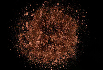 Explosion of brown powder on black background.