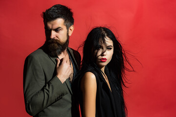 Young couple in love spends time together. Close up studio fashion portrait of stylish young pretty couple in love hugs. Confident People on red.